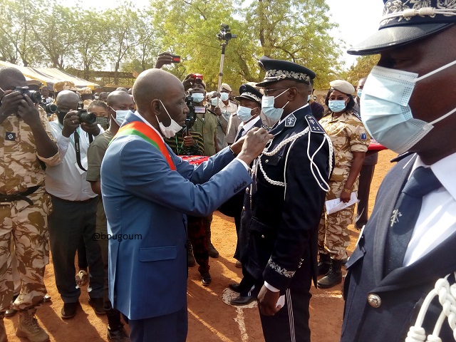 Le colonel André Roch Compaoré, Grand-Chancelier des Ordres burkinabè, accrochant une médialle à un décoré
