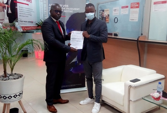 Le directeur général de SUNU Assurances IARD Burkina Faso remettant un contrat d'un client SGBF