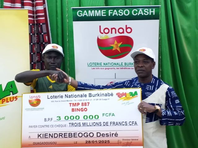 Le directeur régional du Centre de la LONAB, Yamba Jean Zida, remettant le chèque au gagnant Désiré Kiendrébéogo