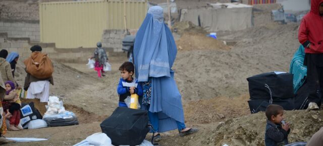 © UNOCHA/Christophe Verhellen Une femme et son enfant marchent dans un camp de déplacés en Afghanistan.