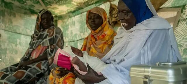 © UNFPA Soudan Une sage-femme tient un nouveau-né dans un camp de personnes déplacées au Soudan.