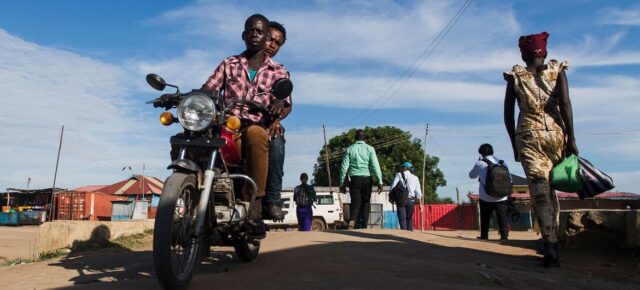 MINUSS/Amanda Voisard Des personnes à moto et à pied sur une route au Soudan du Sud, près de la mission de l'ONU au Soudan du Sud (MINUSS)